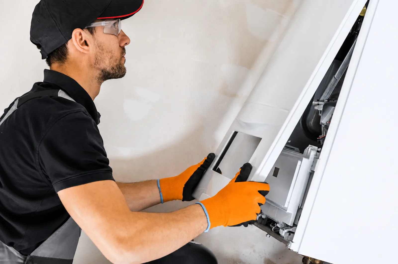 EP Plumbing, Heating & Air technician opening the front panel of a wall-mounted heating unit for service