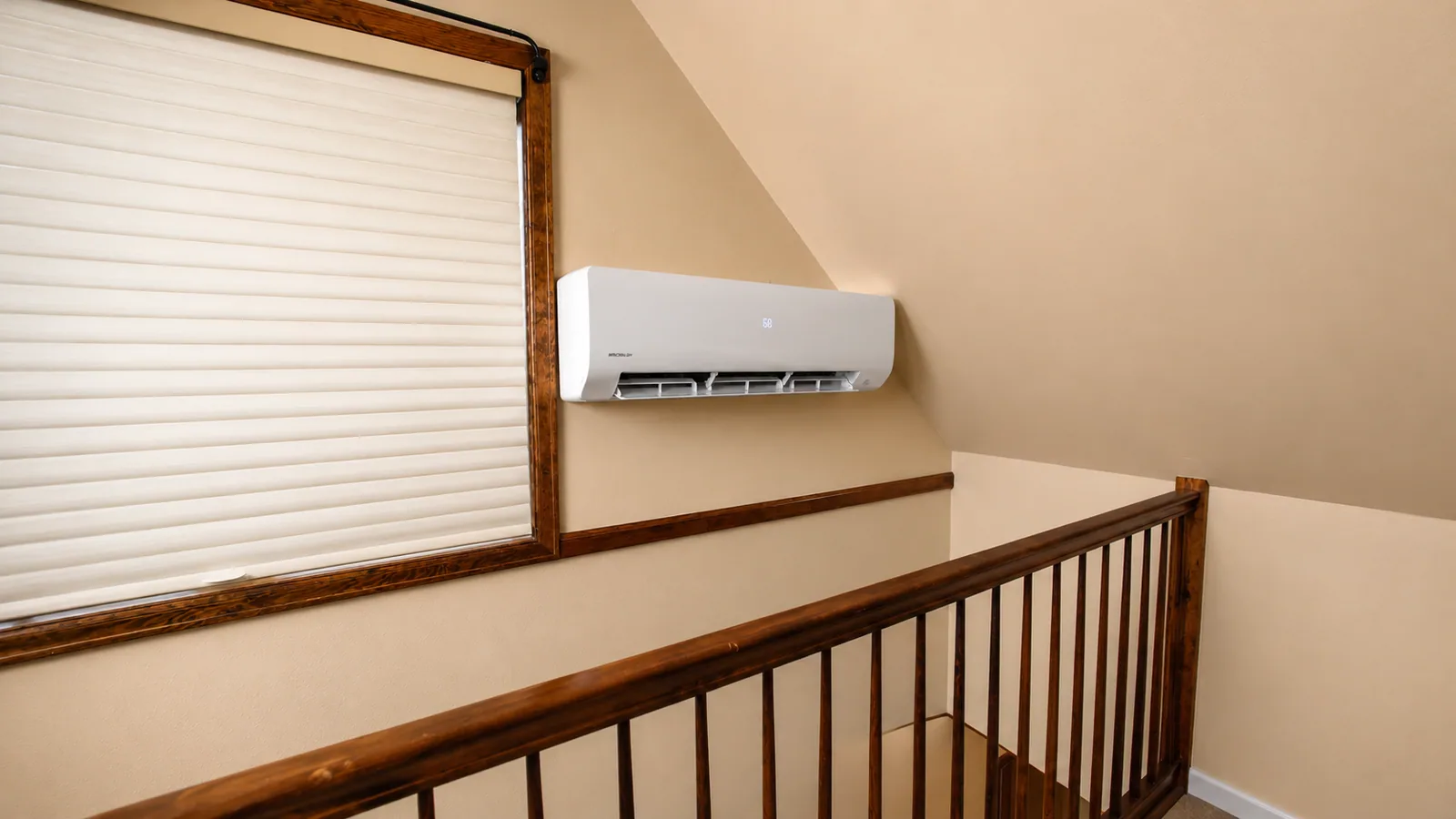 Ductless mini split head mounted on a stairwell wall, display reading 68 degrees