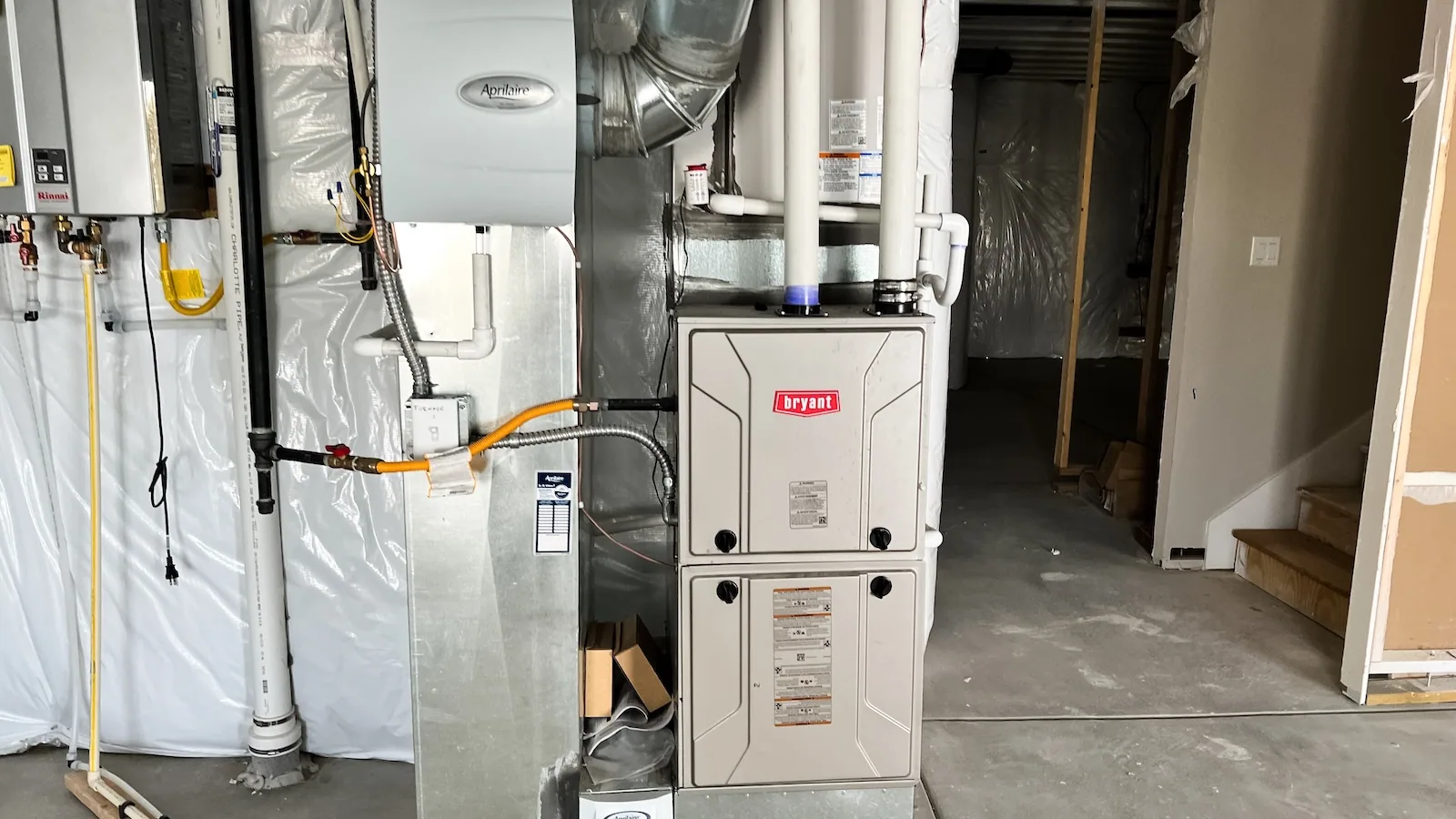 Newly installed Bryant furnace beside a tankless water heater in a Longmont basement mechanical room