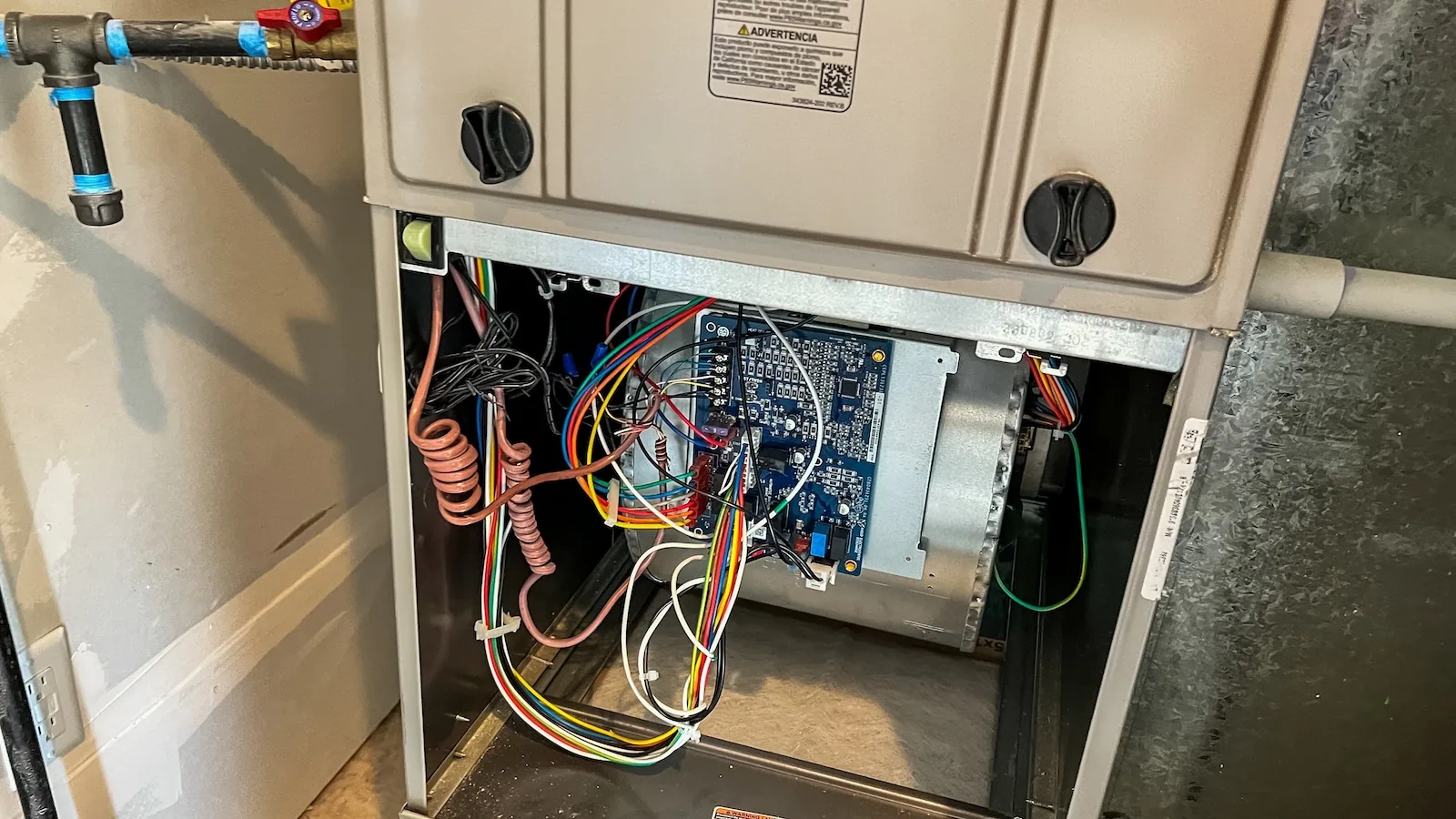 Open furnace cabinet showing the control board and wiring during a repair