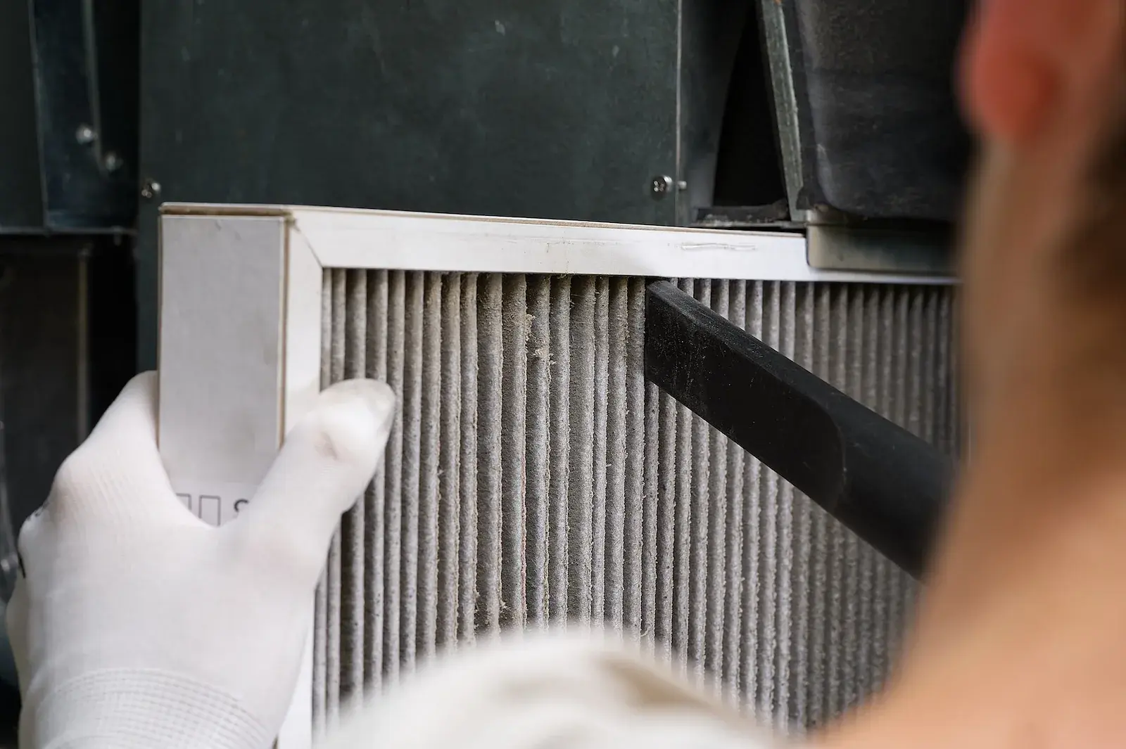 Technician vacuuming dust from a furnace air filter